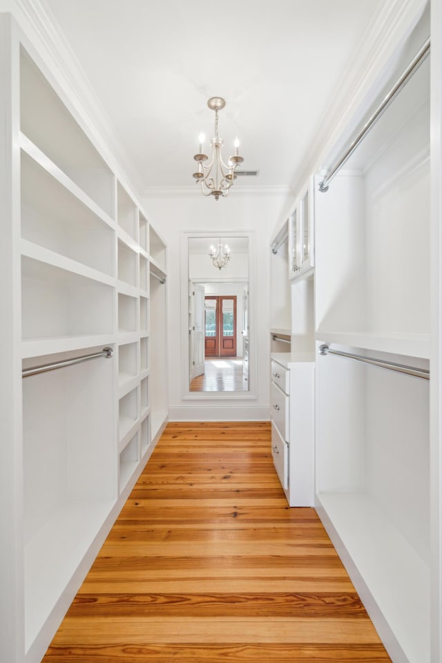 walk in closet featuring light hardwood / wood-style floors and an inviting chandelier