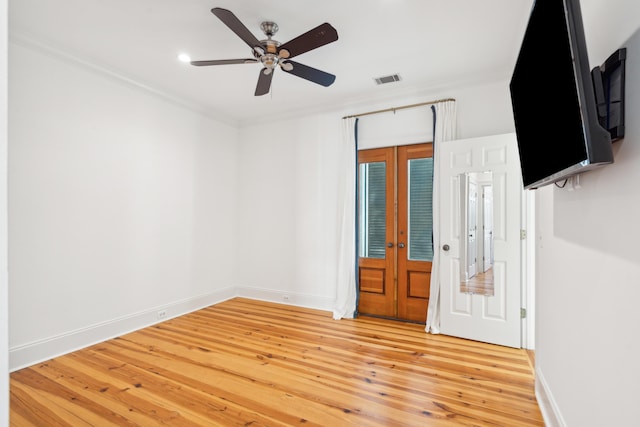 spare room featuring ceiling fan, crown molding, light hardwood / wood-style floors, and french doors