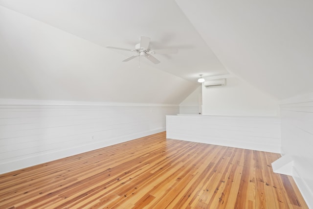 additional living space with a wall unit AC, ceiling fan, lofted ceiling, and light hardwood / wood-style flooring