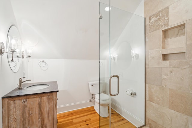 bathroom featuring toilet, a shower with door, wood-type flooring, vaulted ceiling, and vanity