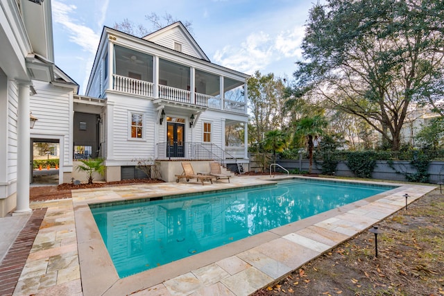 rear view of house featuring a fenced in pool, a sunroom, and a patio