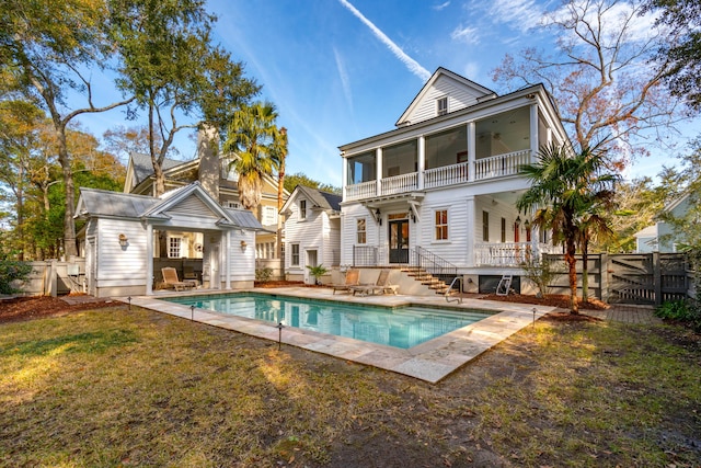 rear view of property with a yard, a patio area, a balcony, and a fenced in pool