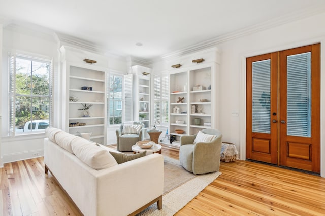 living area with crown molding, a healthy amount of sunlight, light hardwood / wood-style flooring, and french doors