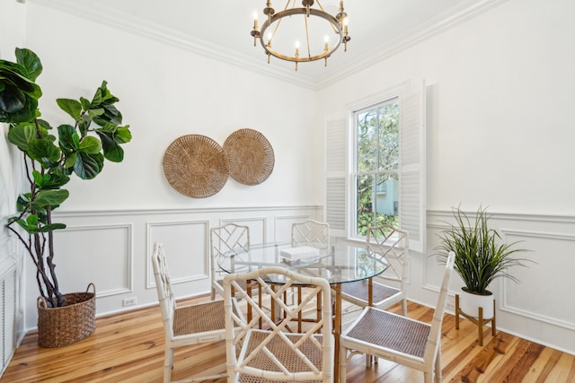 dining space featuring hardwood / wood-style flooring, crown molding, and a notable chandelier