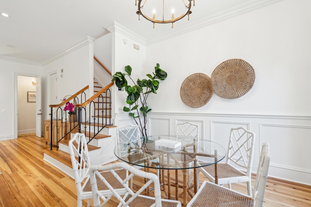 dining space featuring ornamental molding, light hardwood / wood-style floors, and a notable chandelier