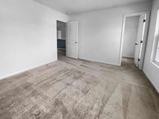 unfurnished bedroom with carpet flooring, a spacious closet, and a closet