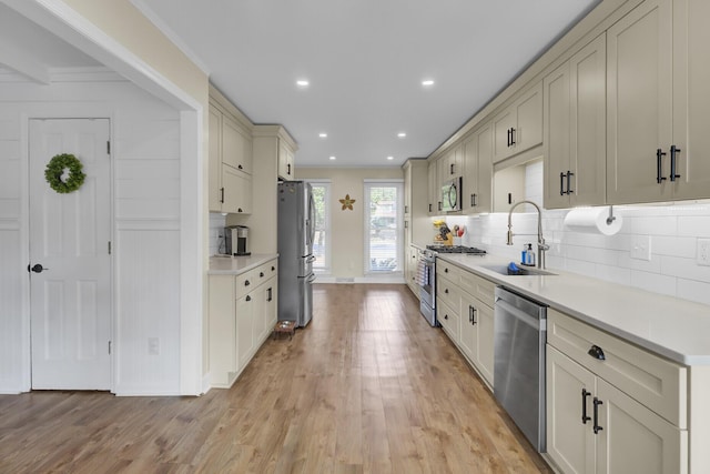 kitchen with stainless steel appliances, tasteful backsplash, sink, and light wood-type flooring