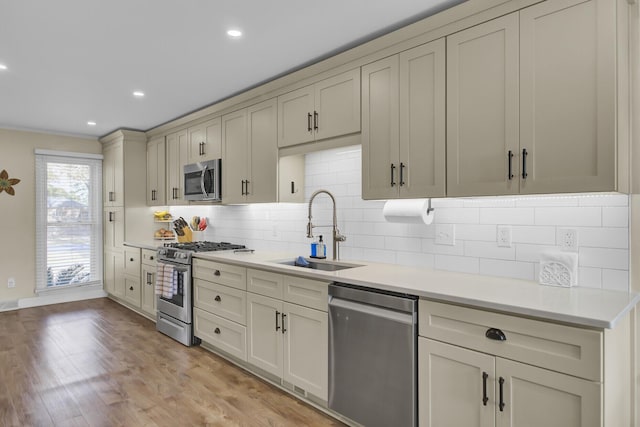 kitchen featuring appliances with stainless steel finishes, tasteful backsplash, sink, light hardwood / wood-style floors, and cream cabinets