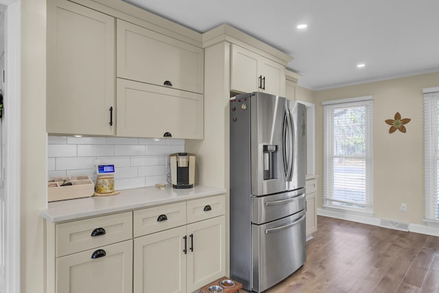 kitchen featuring crown molding, decorative backsplash, hardwood / wood-style flooring, and stainless steel refrigerator with ice dispenser