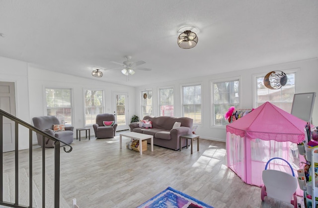 living room featuring vaulted ceiling, a healthy amount of sunlight, ceiling fan, and light hardwood / wood-style floors