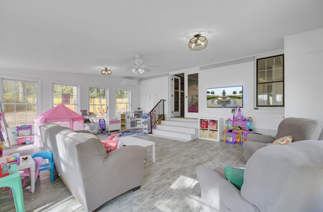 living room featuring a wall mounted air conditioner, light hardwood / wood-style floors, and ceiling fan