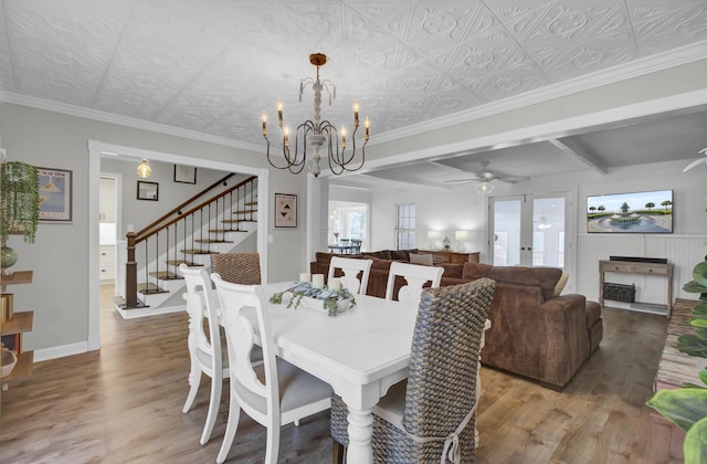 dining space featuring crown molding, wood-type flooring, and ceiling fan with notable chandelier