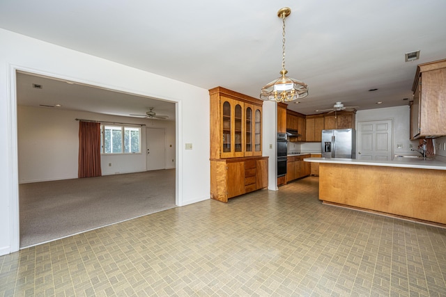 kitchen featuring kitchen peninsula, stainless steel fridge, ventilation hood, sink, and hanging light fixtures