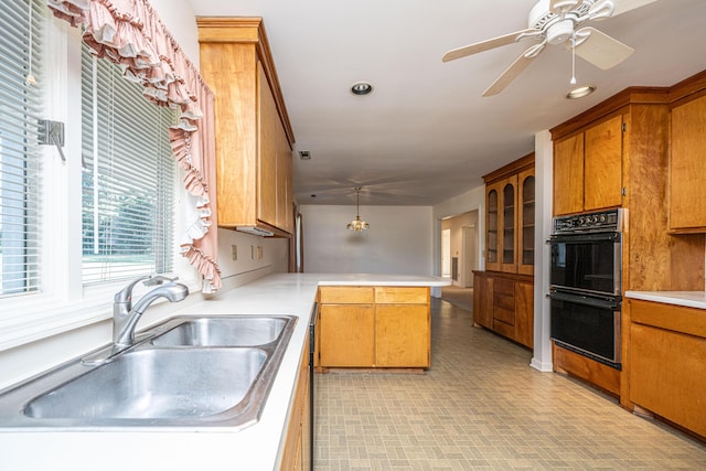 kitchen featuring hanging light fixtures, sink, ceiling fan, double oven, and kitchen peninsula