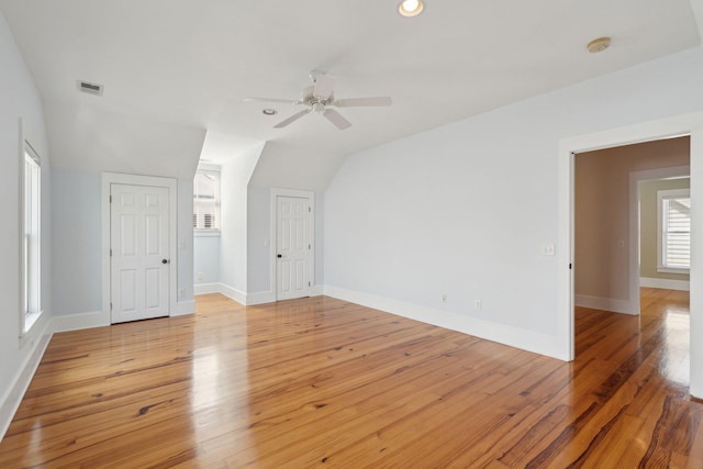 interior space with visible vents, baseboards, ceiling fan, light wood-style floors, and lofted ceiling