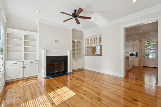 unfurnished living room with recessed lighting, light wood-style flooring, crown molding, a fireplace with flush hearth, and ceiling fan