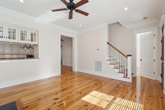 unfurnished living room with a ceiling fan, visible vents, light wood-type flooring, and stairs