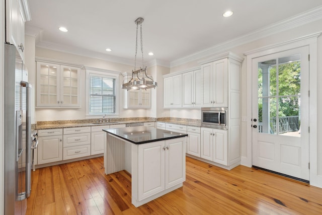kitchen with light wood-style floors, pendant lighting, white cabinetry, a center island, and appliances with stainless steel finishes