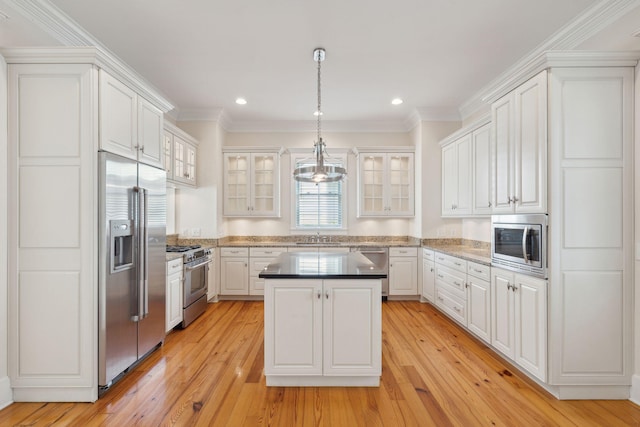 kitchen featuring hanging light fixtures, white cabinets, a center island, and built in appliances