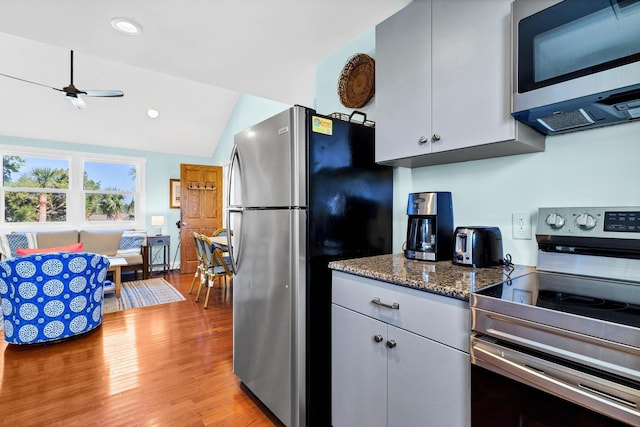 123 Jungle Rd, Edisto Island, SC 29438 - kitchen with appliances with stainless steel finishes, light wood-type flooring, ceiling fan, vaulted ceiling, and dark stone countertops