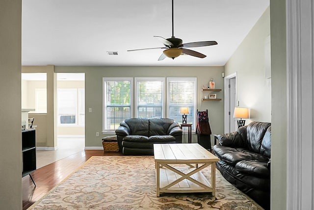living area featuring baseboards, ceiling fan, visible vents, and wood finished floors