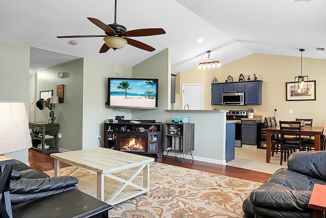 living area with ceiling fan, visible vents, wood finished floors, lofted ceiling, and a glass covered fireplace