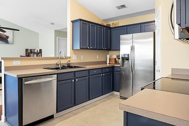 kitchen featuring visible vents, a peninsula, a sink, vaulted ceiling, and stainless steel appliances