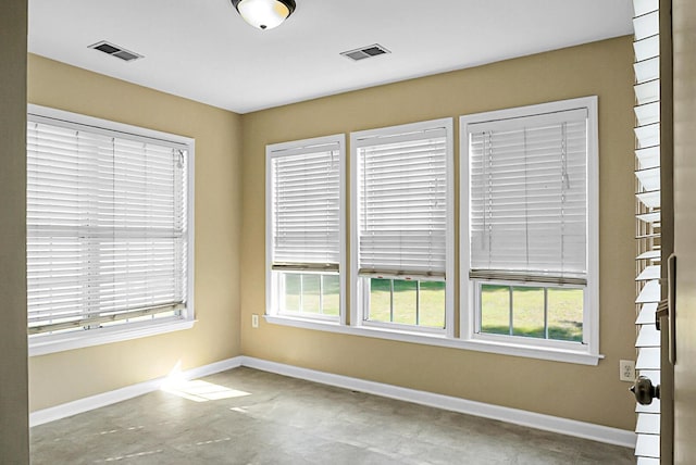 empty room featuring baseboards, visible vents, and plenty of natural light