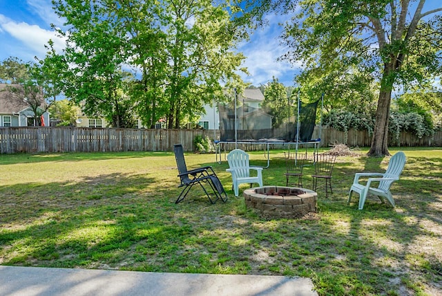 view of yard with a fire pit, a fenced backyard, and a trampoline