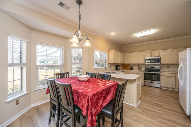 dining space with a notable chandelier, sink, light wood-type flooring, and crown molding