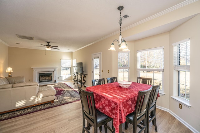 dining space featuring light hardwood / wood-style flooring, a wealth of natural light, and crown molding