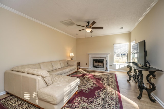 living room featuring a high end fireplace, light hardwood / wood-style flooring, ceiling fan, and ornamental molding