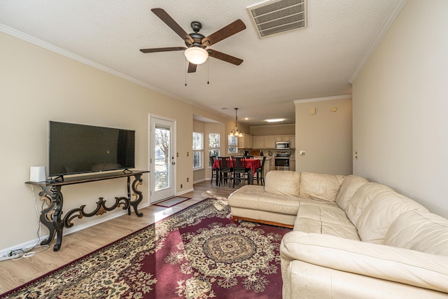 living room with ceiling fan with notable chandelier, ornamental molding, a textured ceiling, and light hardwood / wood-style flooring