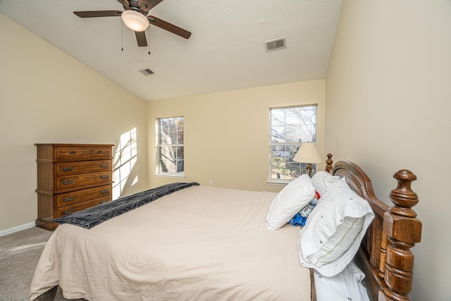 carpeted bedroom with a textured ceiling, multiple windows, ceiling fan, and lofted ceiling