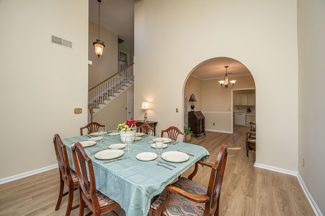 dining space with a chandelier, a high ceiling, light wood-type flooring, and crown molding