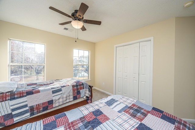 bedroom featuring ceiling fan, a closet, carpet floors, and a textured ceiling