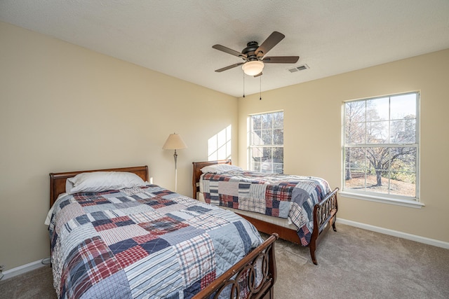 carpeted bedroom with multiple windows, ceiling fan, and a textured ceiling