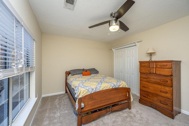 carpeted bedroom featuring ceiling fan, a closet, and a textured ceiling