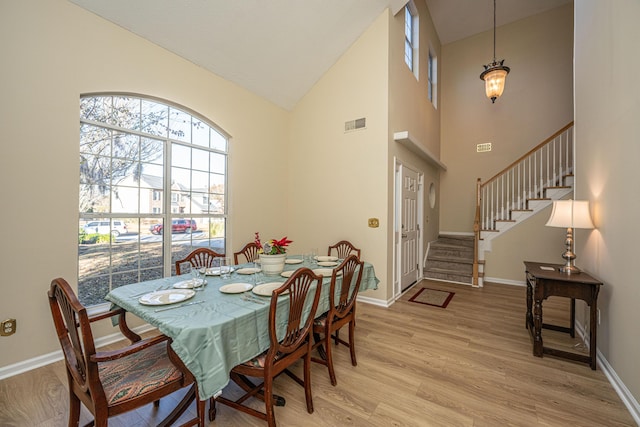 dining space featuring high vaulted ceiling and light hardwood / wood-style flooring