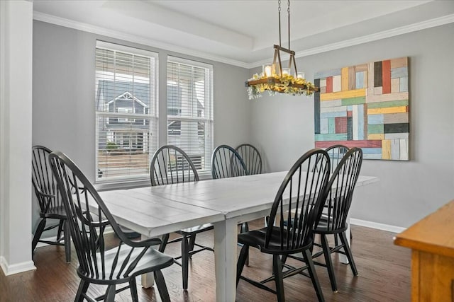 dining space featuring crown molding, dark hardwood / wood-style floors, a raised ceiling, and an inviting chandelier