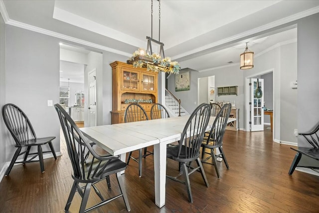 dining room featuring crown molding, dark hardwood / wood-style floors, a notable chandelier, and a tray ceiling