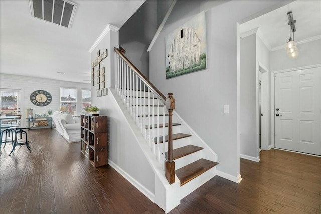 staircase with ornamental molding and hardwood / wood-style floors