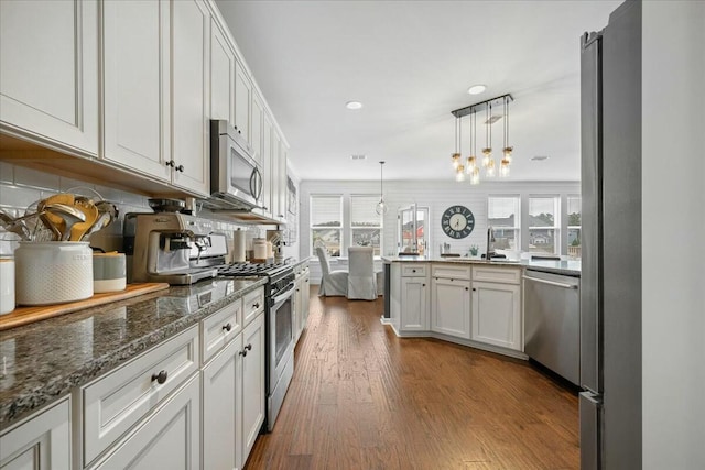 kitchen featuring plenty of natural light, appliances with stainless steel finishes, decorative light fixtures, and white cabinets