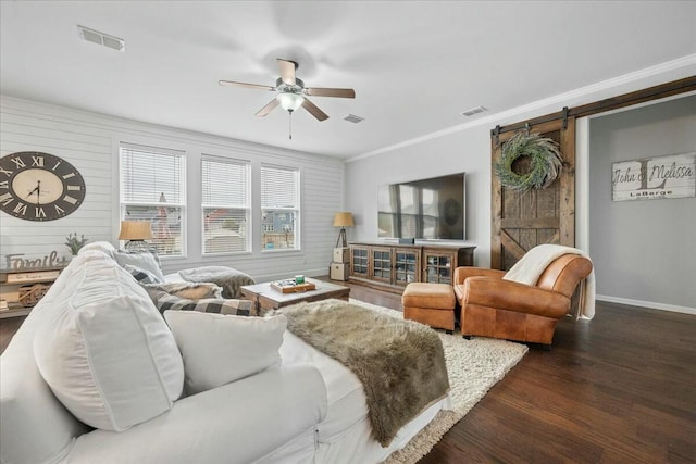 living room with crown molding, ceiling fan, a barn door, and dark hardwood / wood-style flooring