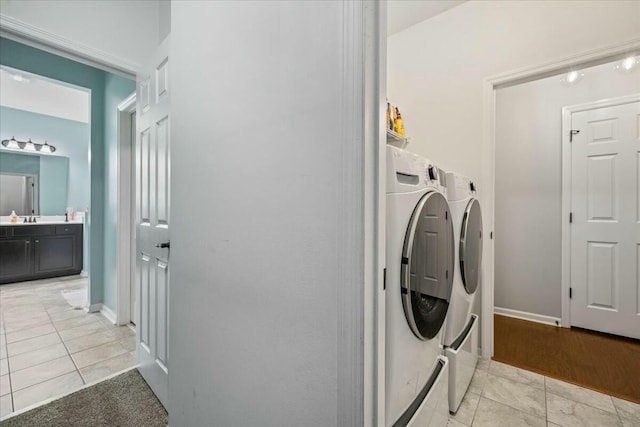 washroom featuring sink, washing machine and clothes dryer, and light tile patterned flooring