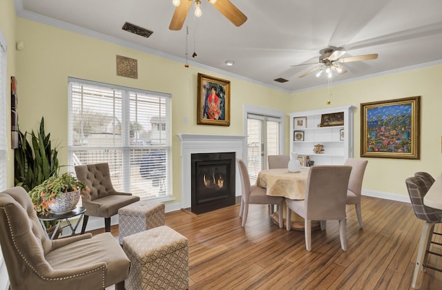 dining space with plenty of natural light, wood-type flooring, and ornamental molding