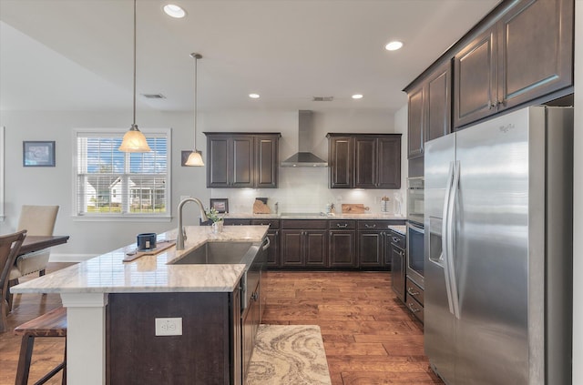 kitchen featuring stainless steel fridge, dark hardwood / wood-style floors, pendant lighting, wall chimney exhaust hood, and sink