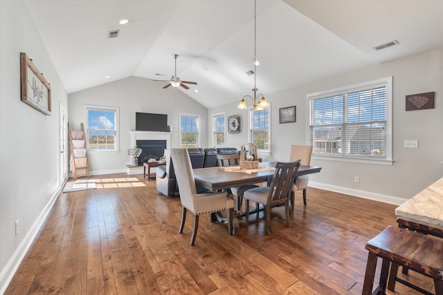 dining area featuring ceiling fan with notable chandelier, lofted ceiling, and dark hardwood / wood-style floors