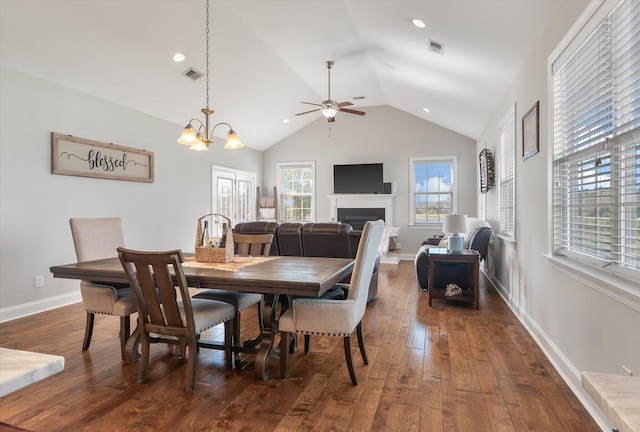 dining space with lofted ceiling, dark hardwood / wood-style flooring, and ceiling fan with notable chandelier