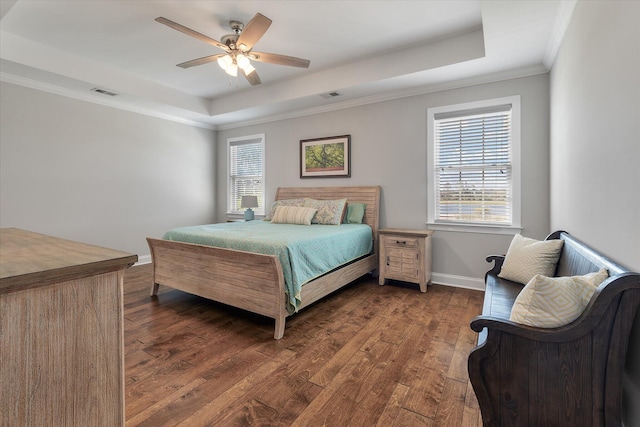 bedroom featuring ceiling fan, a tray ceiling, ornamental molding, and dark hardwood / wood-style flooring